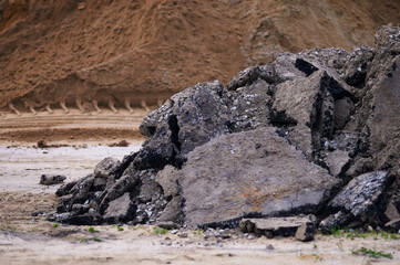 Pieces of asphalt in a heap during road works. Selective focus. A pile of sand is blurred in the...