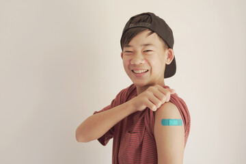 Mixed Asian teen boy showing his arm with blue bandage after got vaccinated or  inoculation, child...