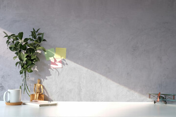 Coffee cup, plant and notebook on white table with concrete wall.