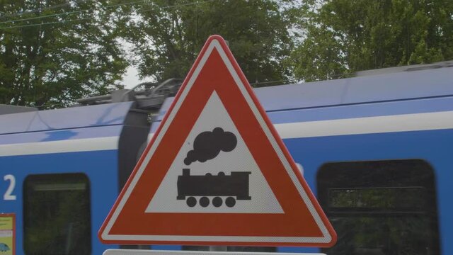 Train passing behind Unguarded level crossing warning sign near a unguarded level crossing