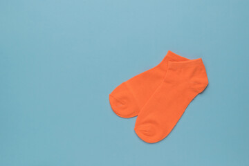 A pair of orange sports socks on a blue background. Flat lay.