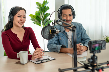 Asian Radio Host Podcast in Studio. Male and female speakers talk through mics and cameras on their...