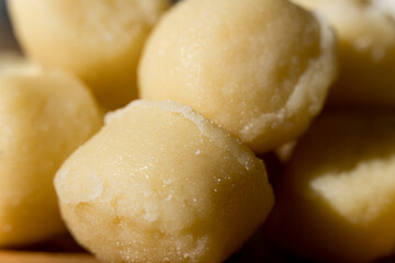 Gnocchi pasta pre-cooked on a wooden board with grated cheese and basil. Macro close up. Selective focus.