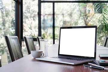 Mockup blank screen laptop computer on wooden table in meeting room.