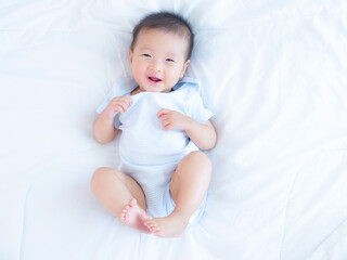 Happy smiling of adorable Asian baby girl on white bed , happy healthy baby girl concept