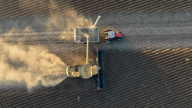 Top down aerial view of combiner harvesting soy beans producing loads of dust.