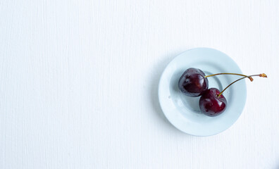 ripe cherries in saucers on a white table