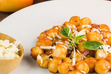 Gnocchi with juice sauce with grated cheese and basil served on the plate. Close-up. Selective focus.