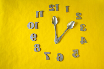 yellow background. numbers. the clock face. gray spoons
