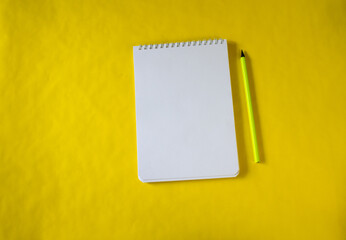 yellow background. a white notebook. pencil.