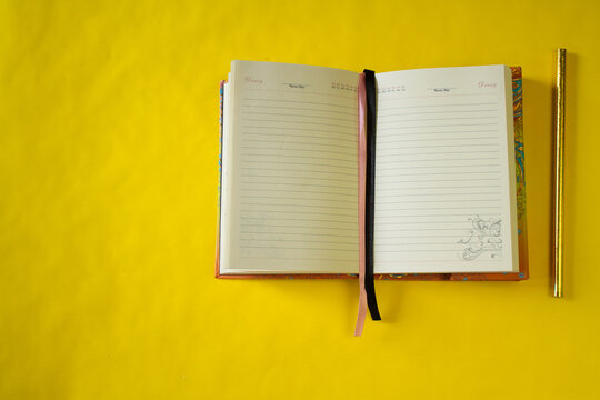 yellow background. a white notebook. pencil.