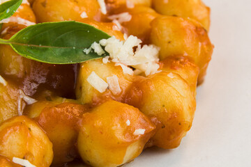 Gnocchi with juice sauce with grated cheese and basil served on the plate. Close-up. Selective focus.