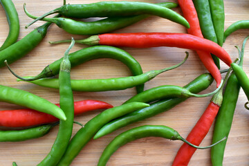 Green and red chillies on a bamboo chopping board. 