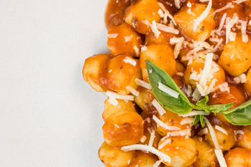 Gnocchi with juice sauce with grated cheese and basil served on the plate. Close-up. Selective focus. Top view.