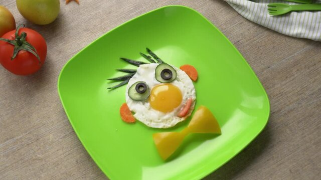 A mother prepares breakfast for a child. A funny picture of scrambled eggs on a plate. Healthy Food Art Snack for Kids. Funny face on a plate. Adorable Kids Snack