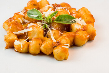 Gnocchi with juice sauce with grated cheese and basil served on the plate. Close-up. Selective focus.