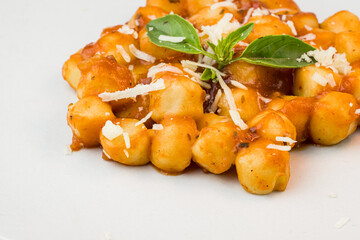 Gnocchi with juice sauce with grated cheese and basil served on the plate. Close-up. Selective focus.