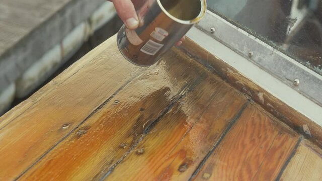 Pouring wood hardener treating affected timber planks with wood rot