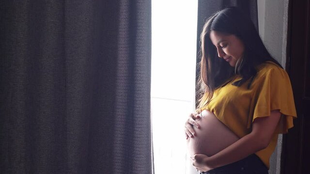 a young pregnant latinx woman in the window