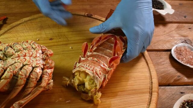 Person In Rubber Gloves cut a  lobster cooking  in table wood Food video close up