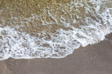 a foamy wave on the sand of the beach