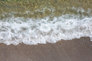 Fototapeta na wymiar a foamy wave on the sand of the beach
