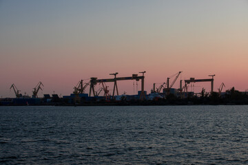 Fototapeta na wymiar silhouettes of harbor cranes in the evening in Mangalia city - Romania 