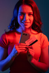 Secure payment. Cyber banking. Internet shopping. Cheerful smiling woman in neon bright red blue...