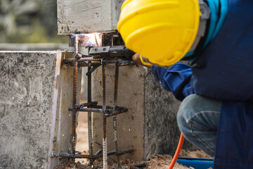 Closeup welder working welding assembly structure between ground beam and pillar prefabricated concrete.