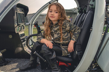 Dreamy tween girl sitting in open cockpit of helicopter
