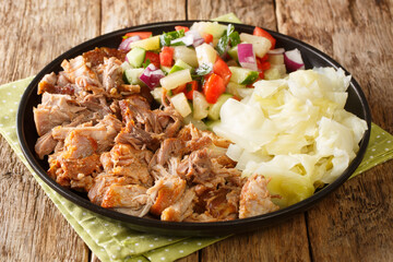 Hawaiian Kalua Pork with stewed cabbage and fresh salad close-up in a plate on the table. horizontal