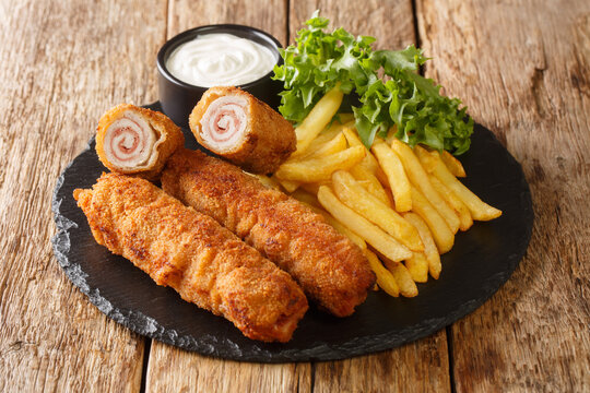 Flamenquin thin Pork Roll with Jamon served with French fries closeup in the slate plate on the table. Horizontal