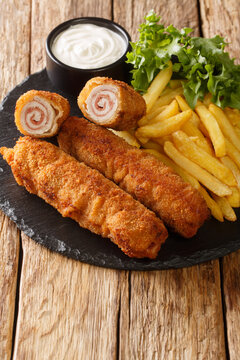 Andalusian Fried Pork Rolls Flamenquines with French fries closeup in the slate plate on the table. Vertical