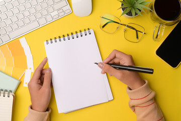 Creative woman holding pen and writing on empty notebook.