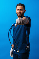 Young arab male doctor standing against blue background