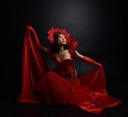 portrait of beautiful young asian woman wearing red corset, posing in gothic horror style with creative hand gestures isolated against  studio background.