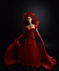 portrait of beautiful young asian woman wearing red corset, posing in gothic horror style with creative hand gestures isolated against  studio background.