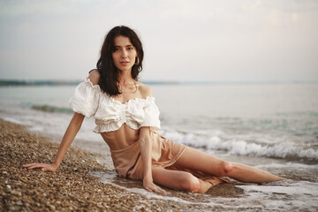 Fototapeta na wymiar Young relaxed woman sitting all alone on empty beach