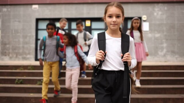 Portrait of preteen schoolchildren of different nationalities with backpacks outdoors on their way to college in warm autumn day. Back to school concept. High quality FullHD footage