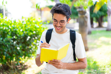 Young student man at outdoors holding a notebook