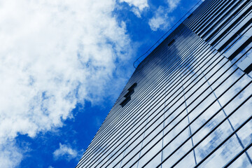 Fototapeta na wymiar Glass skyscraper building with cloudy blue sky background