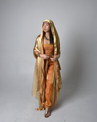 Full length portrait of pretty young asian woman wearing golden Arabian robes like a genie,...