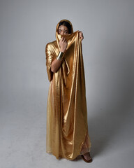 Full length portrait of pretty young asian woman wearing golden Arabian robes like a genie,...