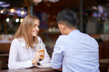 Happy young woman enjoying romantic date with boyfriend at cafe table