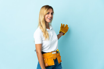 Young blonde Uruguayan electrician woman isolated on blue background extending hands to the side...