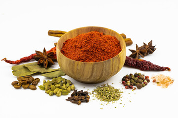 A bowl of paprika and spices around it isolated on a white background.