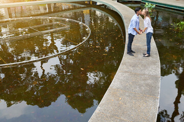 Happy young multi-ethnic couple in love holding hands and kissing when walking in city park