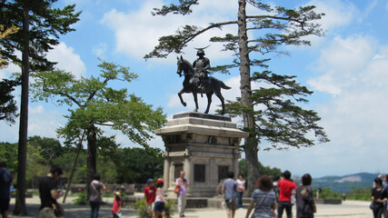 観光客が仙台城趾の伊達政宗騎馬像を観る風景