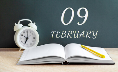 february 09. 09-th day of the month, calendar date.A white alarm clock, an open notebook with blank...
