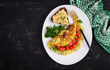 Breakfast. Omelette with zucchini, cheese and tomatoes salad with sandwich on white plate.  Frittata - italian omelet. Top view, flat lay